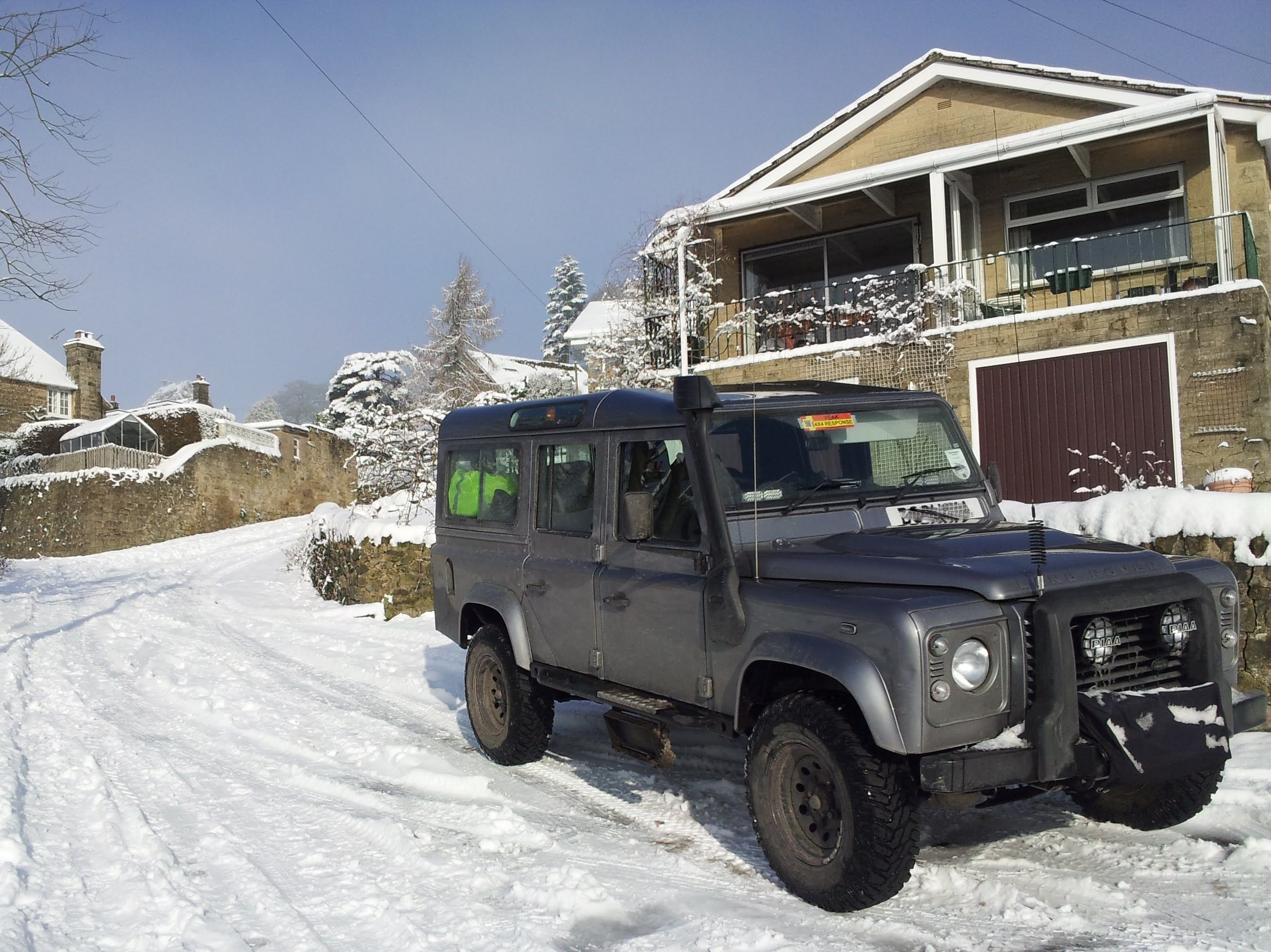 A Peak 4x4 Response Land Rover parked outside a house in the snow